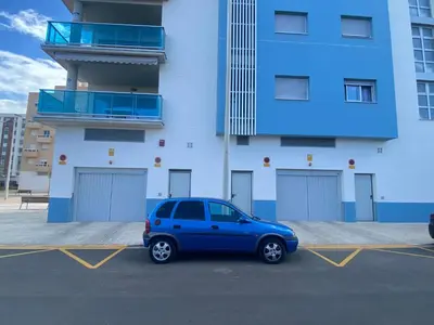 a blue car parked in a parking lot in front of a building at VerdeMar 5 (Playa Puerto de Sagunto) in Puerto de Sagunto