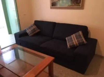 a living room with a black couch and a coffee table at Apartamento frente al mar en Playa Patacona in Valencia