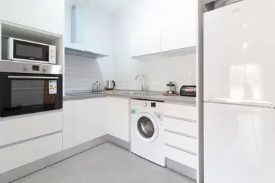 a white kitchen with a washing machine and a microwave at Global Vacacional, Apartamento con gran terraza en la playa de Canet in Canet de Berenguer