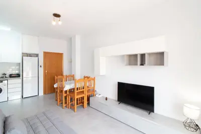 a kitchen and dining room with a table and a television at Global Vacacional, Apartamento con gran terraza en la playa de Canet in Canet de Berenguer