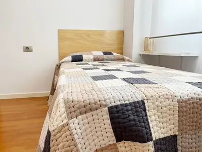 a bedroom with a bed with a quilt on it at Global Vacacional, Apartamento céntrico de 4 dormitorios in Puerto de Sagunto