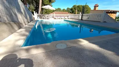 a swimming pool with blue water and a white fence at Chalet El Tochar in Valencia