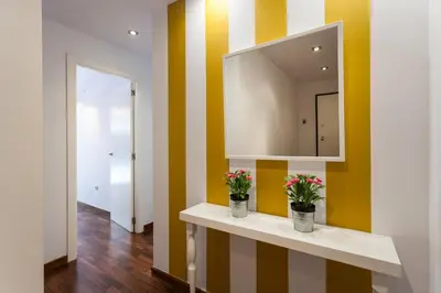 a hallway with yellow and white striped walls and two vases with flowers at Baron Suites in Valencia