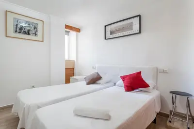two beds in a white room with red pillows at apartamento con terraza in Valencia