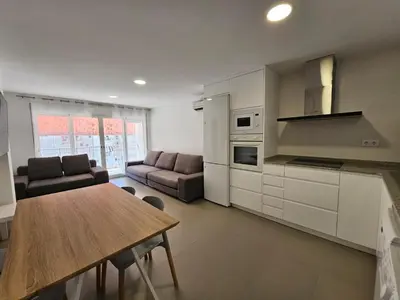 a kitchen and living room with a table and a couch at Apartamento a pie de playa I in Faro de Cullera