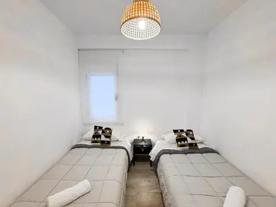 two beds in a room with white walls and a chandelier at NUEVO, a 60 metros de la playa y con vistas laterales al mar in Cullera