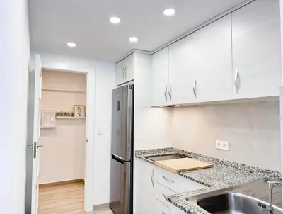 a kitchen with white cabinets and a stainless steel refrigerator at NUEVO, a 60 metros de la playa y con vistas laterales al mar in Cullera