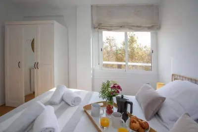 a white bedroom with a bed with a tray of food on it at SingularStays Benimaclet in Valencia