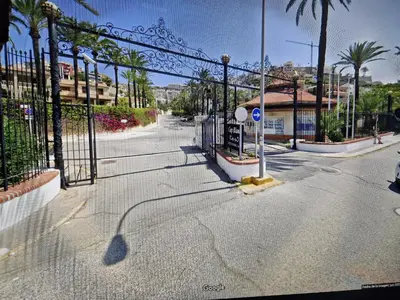 a gate on a street with palm trees and a building at Apartamentos Bon Amb in Faro de Cullera