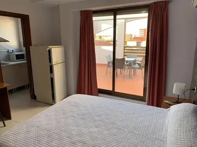 a bedroom with a bed and a kitchen with a balcony at Apartamento Castillo - Alquiler de temporada in Puerto de Sagunto