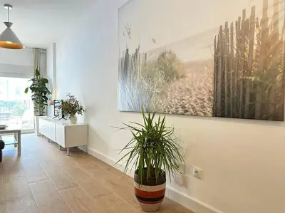 a living room with a potted plant on the wall at Your Poolside Paradise by the Sea in Port Saplaya