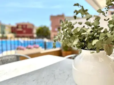 a white vase with a plant in it on a table at Your Poolside Paradise by the Sea in Port Saplaya