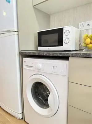 a kitchen with a washing machine and a microwave at Your Poolside Paradise by the Sea in Port Saplaya