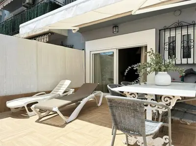 a patio with a table and chairs and a vase at Your Poolside Paradise by the Sea in Port Saplaya
