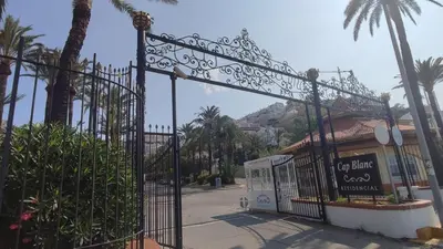 a gate in front of a building with palm trees at Una casa con vistas in Faro de Cullera