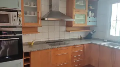 a kitchen with wooden cabinets and a stove top oven at Una casa con vistas in Faro de Cullera