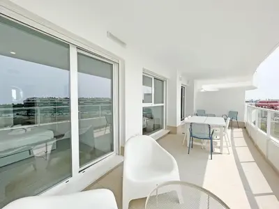 a white apartment with a balcony with a table and chairs at Global Vacacional, Apartamento con terraza, vistas al mar y a la piscina in Canet de Berenguer