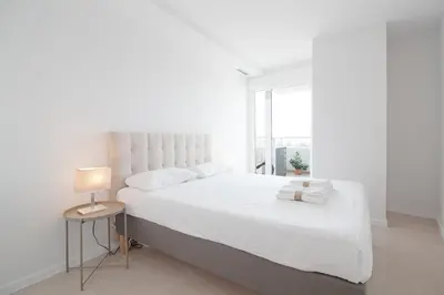 a white bedroom with a white bed and a lamp at Global Vacacional, Moderno apartamento con terraza en Gran Canet in Canet de Berenguer