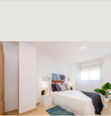 a white bedroom with a large bed and a window at Vacaciones perfectas. in Paterna
