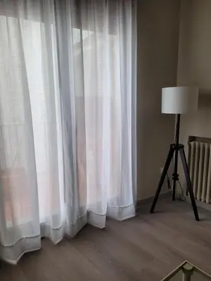 a room with a window with white curtains and a lamp at La Casa Alandí con garaje privado in Sagunto