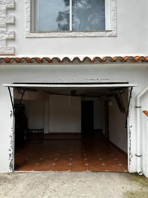 an open garage under a building with a window at Villa Rosa Rasero in Serratella