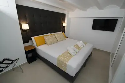 a bedroom with a white bed and a television at BET Apartments - Suites Puerto Valencia in Valencia