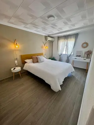 a bedroom with a large white bed and a table at DJcumar Apartamento en Cullera comodo y bien ubicado in Cullera