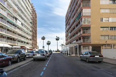 a city street with parked cars and tall buildings at Amador, 4-J in Cullera