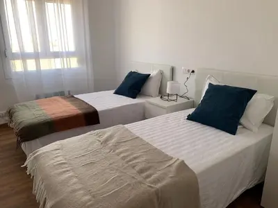two beds in a room with white walls and blue pillows at Sueca 1 in Sueca