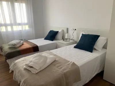 two beds in a white room with blue pillows at Sueca 1 in Sueca
