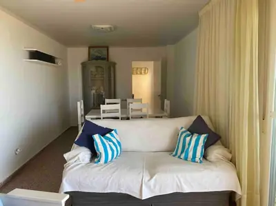 a living room with a white couch with blue and white pillows at Alquiler de temporada Canet Playa - en primera linea in Canet de Berenguer