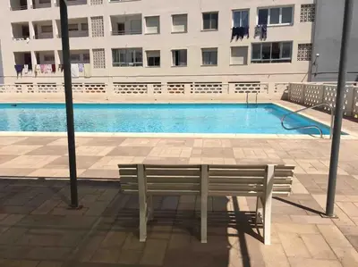 a bench sitting in front of a swimming pool at Alquiler de temporada Canet Playa - en primera linea in Canet de Berenguer