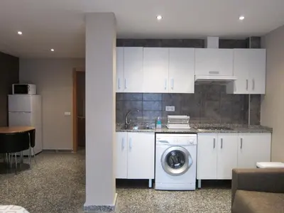 a kitchen with white cabinets and a washing machine at Apartamentos Abastos in Valencia