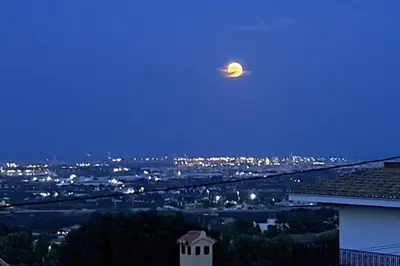 a moon in the sky over a city at night at Casa en Valencia, piscina, cerca de golf, playas, moto Gp in Valencia