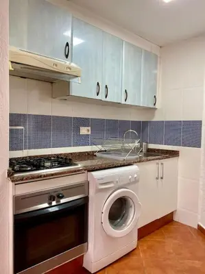 a kitchen with a washing machine and blue cabinets at Sol y Mar in Puebla de Farnals