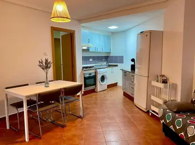 a kitchen with a table and a kitchen with a refrigerator at Sol y Mar in Puebla de Farnals