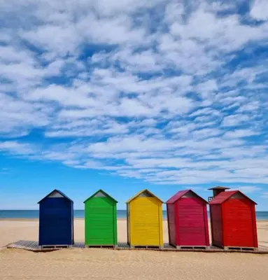 a row of colorful beach huts on the beach at ROSA in Llaurí