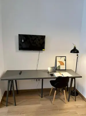 a desk with a chair and a television on a wall at Victoria Inn Apartment in Valencia