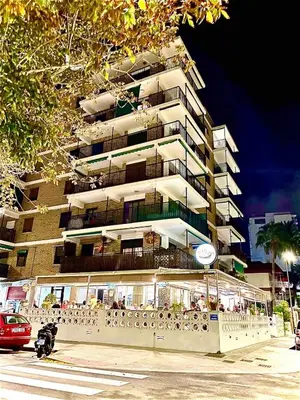 a tall apartment building with people sitting outside of it at Brisa Marina in Las Canteras