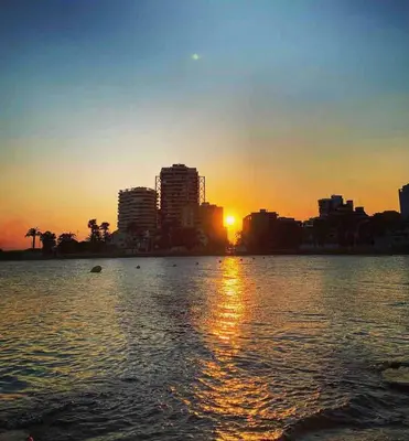 a sunset over a large body of water with a city at Brisa Marina in Las Canteras