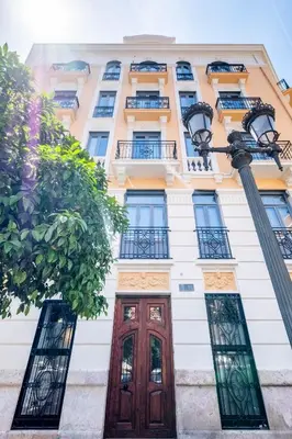 a tall white building with windows and a wooden door at New and Modern Apartment with Comfy Beds in Valencia