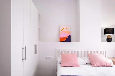 a bedroom with white walls and a bed with pink pillows at Beautiful Suite with Private Terrace in Valencia