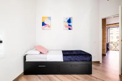 a bed in a room with a white wall at Well Lit and Creatively Designed Apartment in Valencia