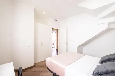 a white bedroom with a bed and a staircase at Spacious Penthouse with Massive Terrace in Valencia