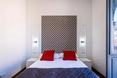 a bedroom with a large bed with two red pillows at BrightHouse with Warm and Friendly Vibes in Valencia