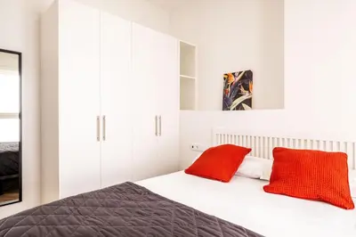 a bedroom with white cabinets and red pillows on a bed at Serene Apartment with a Relaxing Atmosphere in Valencia
