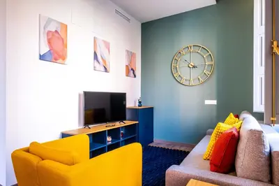 a living room with a yellow couch and a clock at Amazing Apartment with aFun and Friendly Atmosphere in Valencia