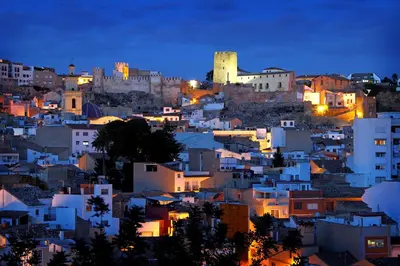 a city lit up at night with a castle at LA TRAVIATA - Buñol in Buñol
