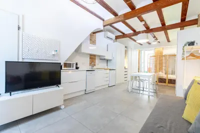a large kitchen with white cabinets and a flat screen tv at ApartUP Las Arenas Beach in Valencia