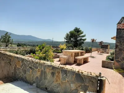 a stone wall with a picnic table and benches at EL ARA DE LOS ORISHAS in Siete Aguas